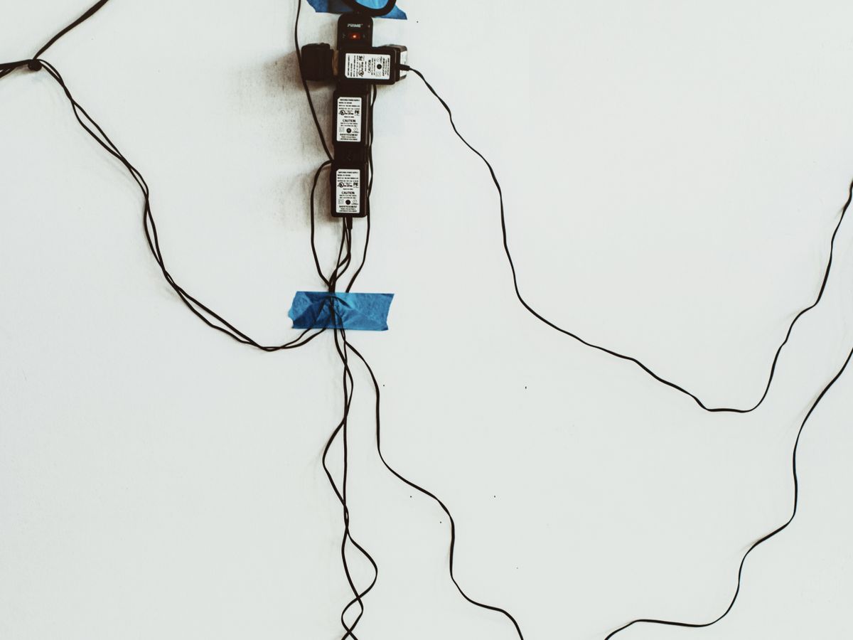 Before: tangled cables and a power strip hanging on a wall