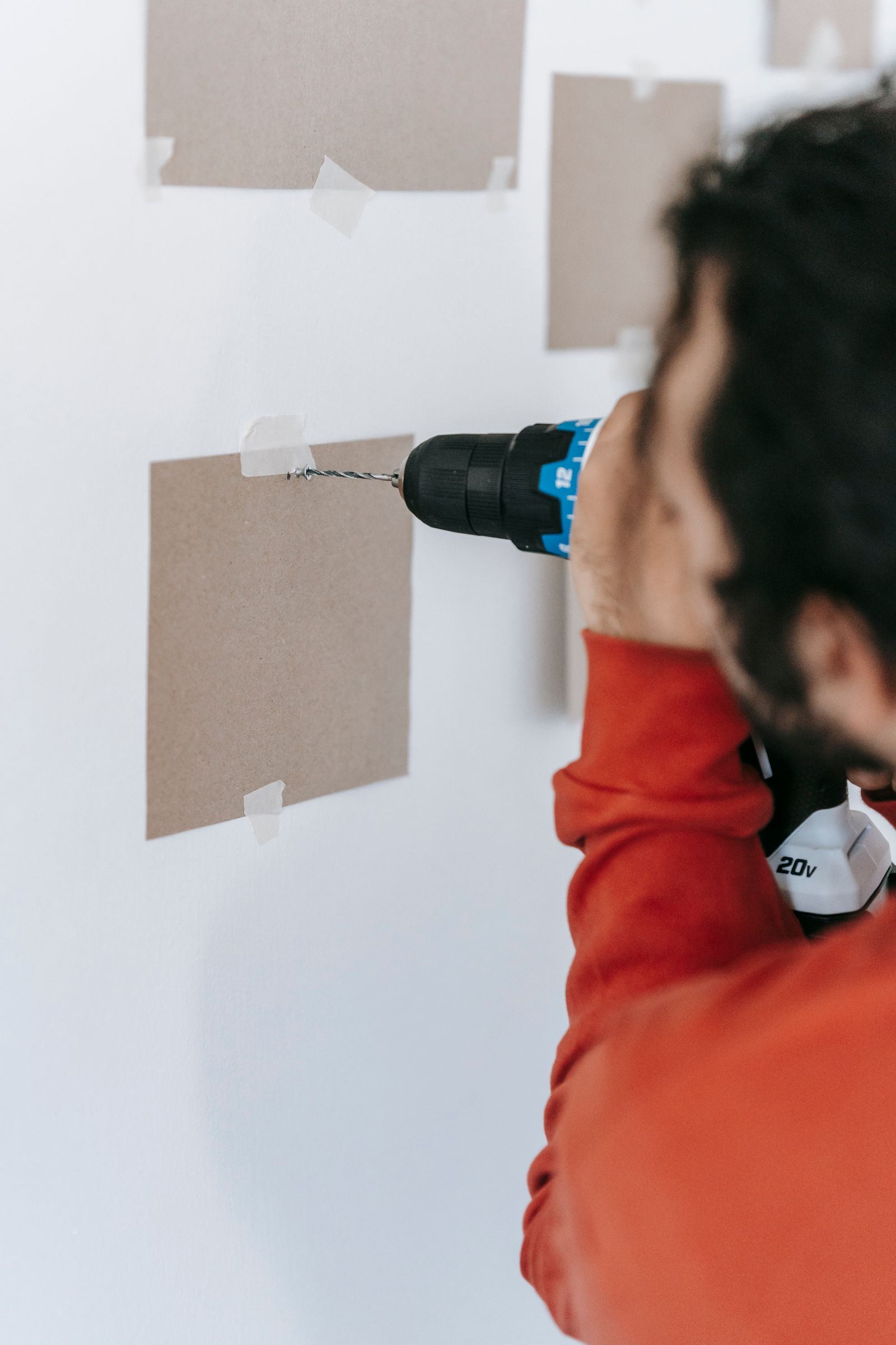 Technician drilling into a wall to install a TV mount