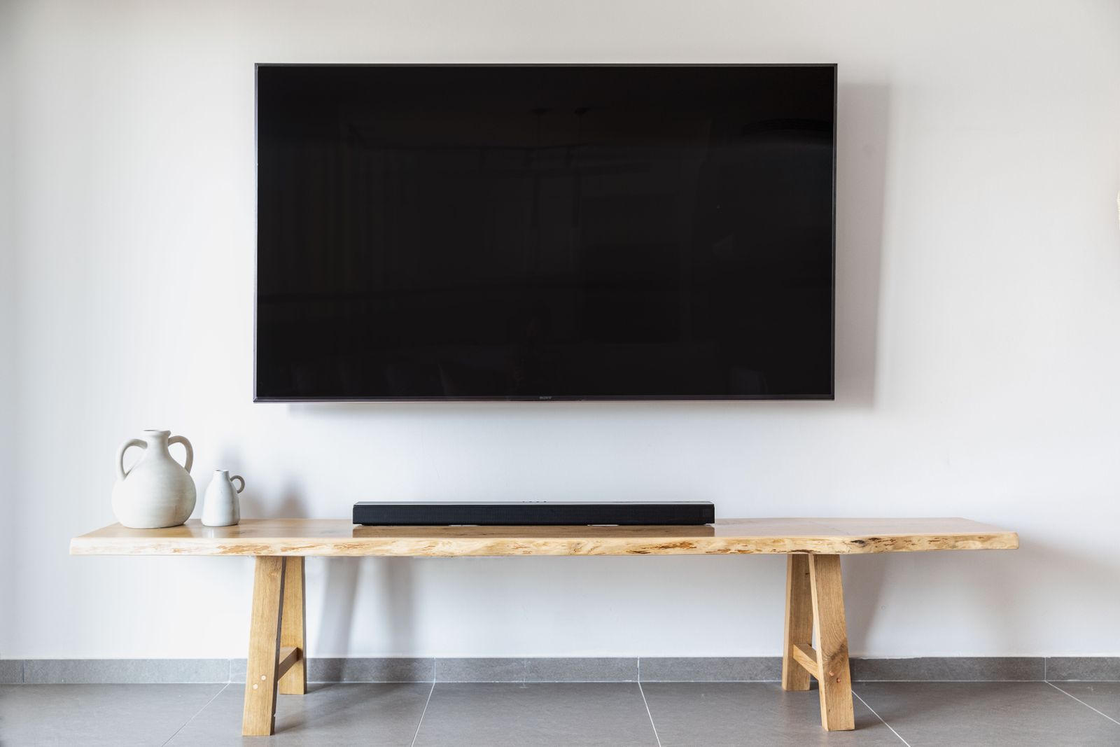 Flat-screen TV mounted on a white wall above a wooden console